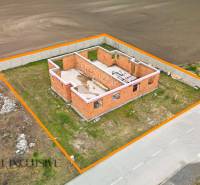 An unfinished family house in Veľké Dvorníky, outlined by an orange line, located by the road.