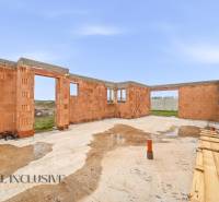 Construction phase of a family house in Veľké Dvorníky with foundations and brick walls.