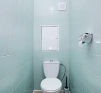 A toilet in a 3-room apartment with light blue tiles and a light-colored floor.