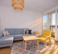 Living room with a sofa, yellow armchair, carpet, and wooden decor flooring in a 3-room apartment.