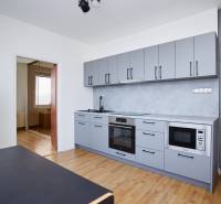 A kitchen in a 3-room apartment with modern appliances and a wooden decor floor.