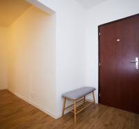 Entrance hall with wood-patterned flooring and a bench in a 3-room apartment.