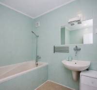 A bathroom in a 3-room apartment with a bathtub, a sink, a mirror, and light blue tiles.