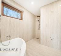 A bathroom in a family house with a bathtub and a shower, the walls have a marble appearance.