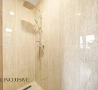 A shower enclosure in a family house with marble tiles.