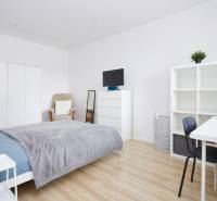 Bedroom in a 2-room apartment with white furniture and a wood-patterned floor.