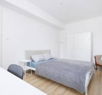 Bedroom of a two-room apartment with a bed, wardrobe, and floor with a wooden decor.