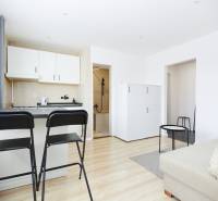 Interior of a 2-room apartment with a kitchen, bar stools, and a wooden decor floor.