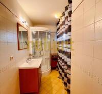 Bathroom in a family house with a sink, shower, and tiles.