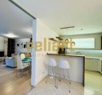 A kitchen and living room in a family house with a bar counter and stools.