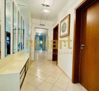 A hallway in a family house with tiles, a mirrored wall, and wooden doors.