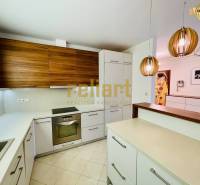 A kitchen in a family house with a kitchen unit, pendant lamps, and built-in appliances.