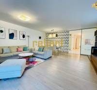Living room in a family house with a sofa, decorations, and a wooden-patterned floor.