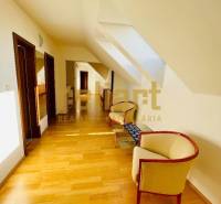 A hallway with a wooden decor floor, skylights, and comfortable armchairs in a family house.