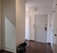 A hallway in a 3-room apartment with white walls and brown tiles.