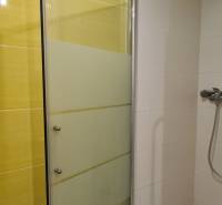 Shower enclosure with doors in a 3-room apartment, combination of yellow and white tiles.