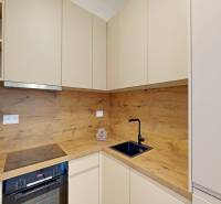 A kitchen in a 2-room apartment with a wooden decor, storage cabinets, and appliances.