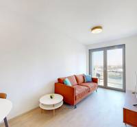 Living room in a two-room apartment with an orange sofa, TV, and balcony doors.