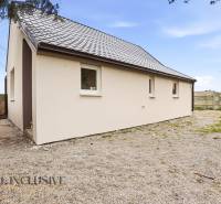 A family house in Dolný Bar with a white facade and a sloped roof on a rocky plot.