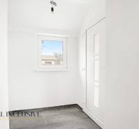 Entrance hall in a family house with a window and light-colored walls, tiled floor.