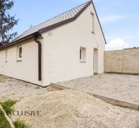A family house in Dolný Bar with a white facade and a sloped roof on a gravel plot.