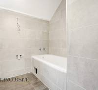 A bathroom in a family house with a bathtub and light tiles on the walls.