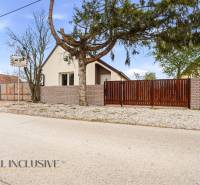 A family house in Dolný Bar with a wall and a gate, surrounded by trees and cement.
