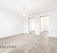 A white room in a family house with a wooden-patterned floor and a bare light bulb.