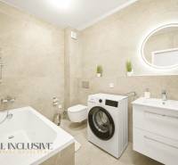 Bathroom with shower, washing machine, and sink in a 4-room apartment with beige tiles.