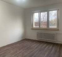 A room with white walls, a wooden decor floor, and a large window in a 2-room apartment.