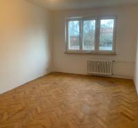 A room in a two-room apartment with a wooden decor floor and a large window.
