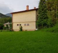 A family house in Blatnica on Blatnica Street surrounded by greenery and trees, with mountains in the background.