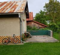A family house in Blatnica with a garden, a bicycle leaning against the wall, a visible wooden shelter.