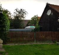 A wooden family house in Blatnica with a wooden fence and a satellite dish.