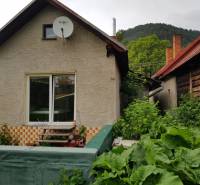 A family house in Blatnica with wooden elements and a garden surrounded by greenery.