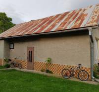 A family house in Blatnica with a metal roof and bicycles in the garden.