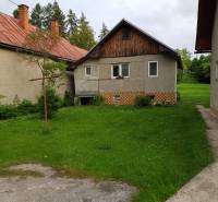 A family house in Blatnica with a front garden and a brick roof, surrounded by green grass.