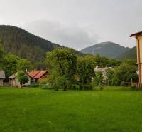A family house in Blatnica surrounded by green trees and mountains.