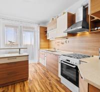 A kitchen in a 2-room apartment with a wooden decor kitchen unit and flooring.