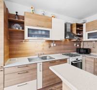 A kitchen in a 2-room apartment with a wooden decor floor and designer lighting.