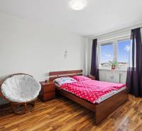 A room in a 2-room apartment with a bed, chair, wardrobe, and floor with a wooden decor.