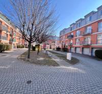Apartment complex with orange facades, trees, and landscaped walkways. Suitable for a one-bedroom apartment.