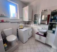 The bathroom in the studio apartment offers a toilet, a washing machine, and shelves by the window.