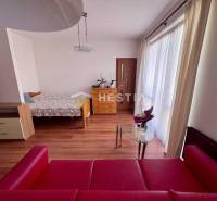In the photograph is a studio apartment, including a bed, a red sofa, and a glass table.