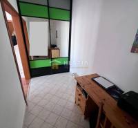 A narrow space with a storage cabinet and a wooden table in a studio apartment.