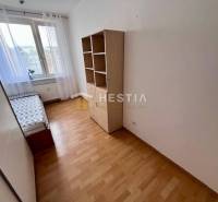 2-room apartment, bed by the window, shelf, floor with wood decor, white wall.