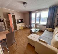 Living room in a two-room apartment with a wood-patterned floor, beige sofa, dining table.