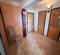 A hallway in a 2-room apartment with tiles, a wardrobe, and a chair.
