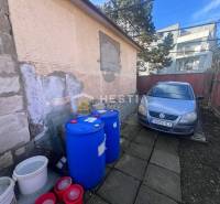 A car next to a building with barrels in the gastro area in Senica.