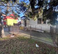 An older house surrounded by a fence and trees near dining spaces in Senica.